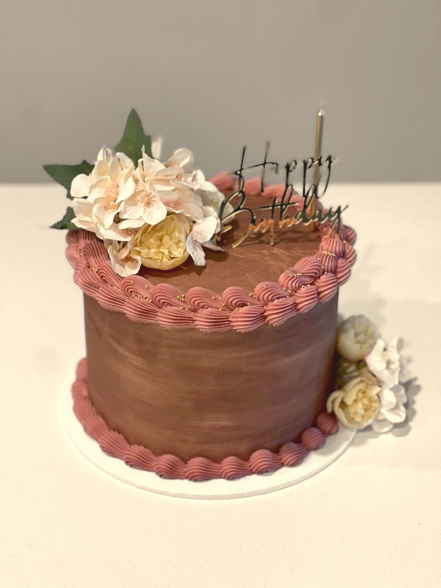 Chocolate cake with dusty-pink piping and cream roses