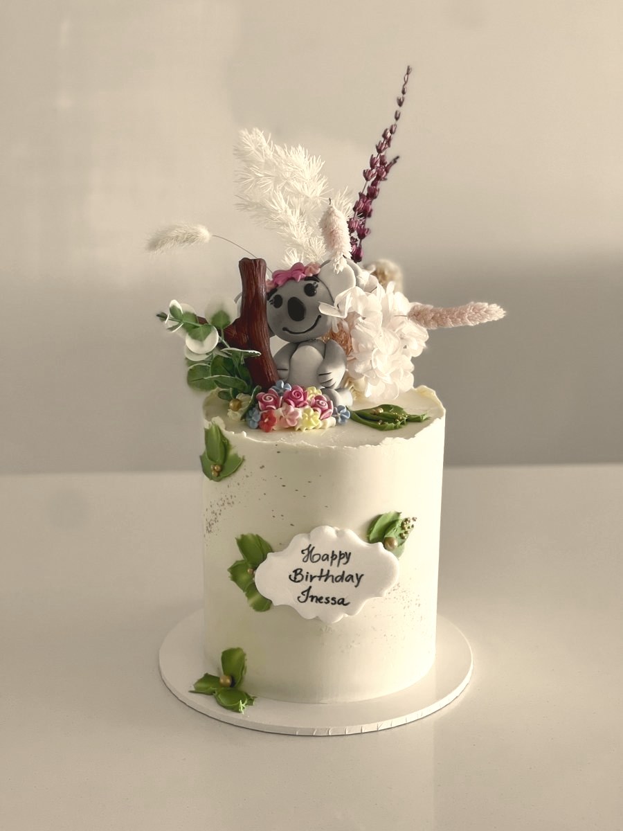 Tall cake with dried flowers and a modelled koala