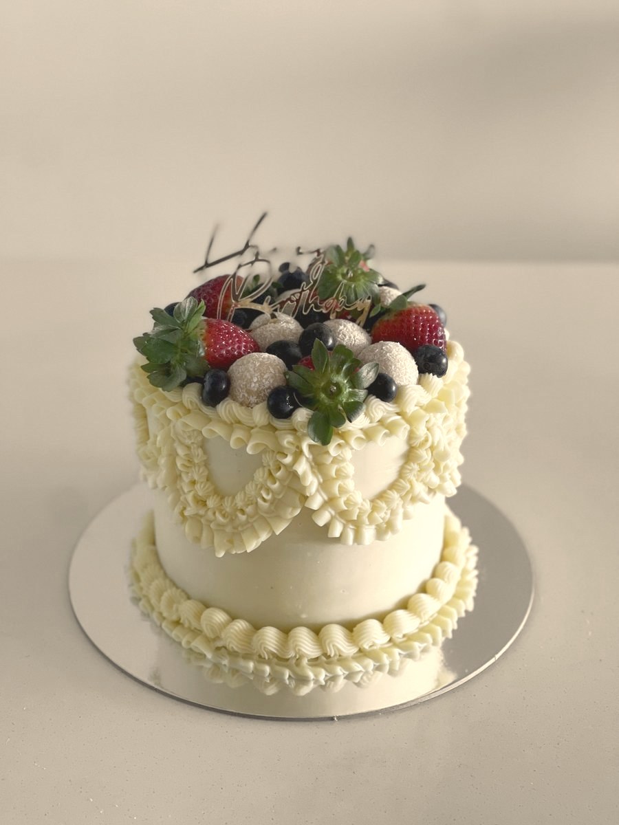 Vintage piped cake topped with berries and herbs