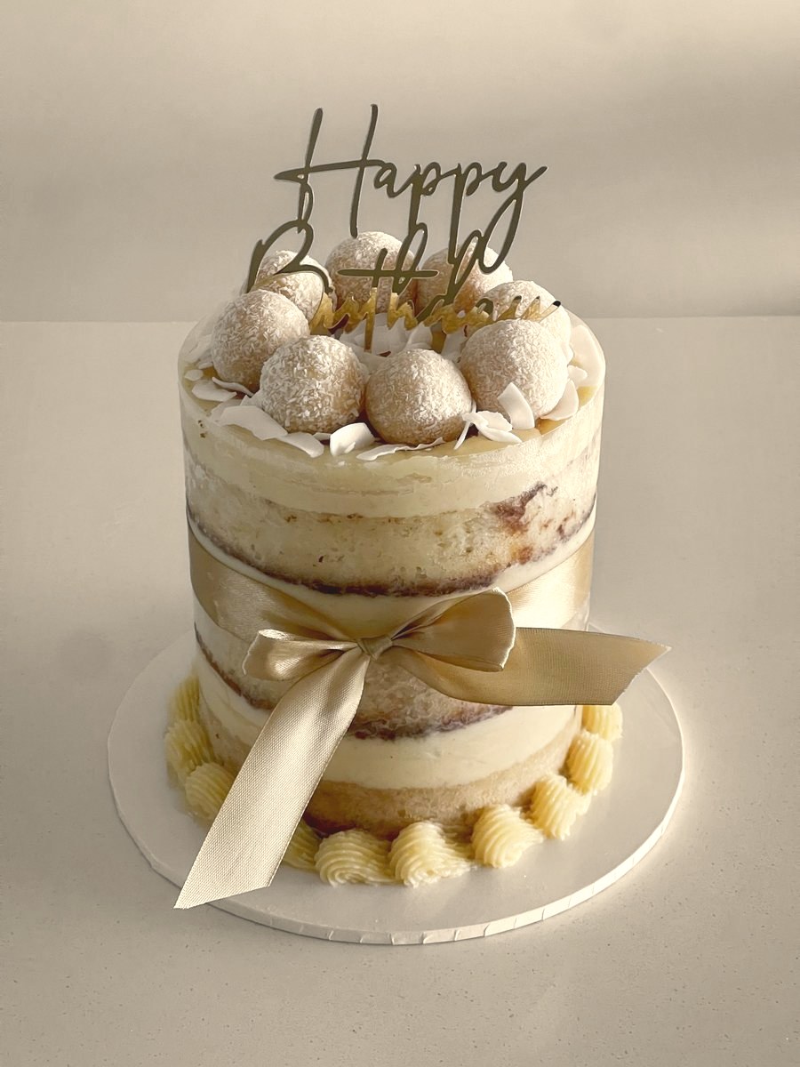 Naked cake tied with a gold ribbon and topped with golden truffles